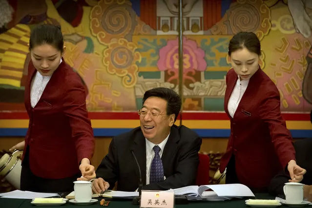Wu Yingjie, center, Communist Party secretary of the Tibetan Autonomous Region, laughs as attendants refill mugs of tea during a group discussion session held on the sidelines of the annual meeting of China's National People's Congress (NPC) in the Tibet Hall of the Great Hall of the People in Beijing, Wednesday, March 6, 2019. The Chinese Communist Party chief for Tibet said on Wednesday that the Dalai Lama has not done a “single good thing” for the region. (Photo by Mark Schiefelbein/AP Photo)