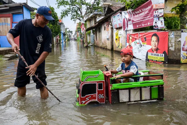 A resident pulls his child who was in a toy truck during a flood in Bojongasih Village, Dayeuhkolot, Bandung Regency, Indonesia on January 8, 2024. Heavy rain last Sunday caused hundreds of houses in Dayeuhkolot to be submerged in floodwater as high as 50 centimeters. (Photo by Dimas Rachmatsyah/ZUMA Press Wire/Rex Features/Shutterstock)