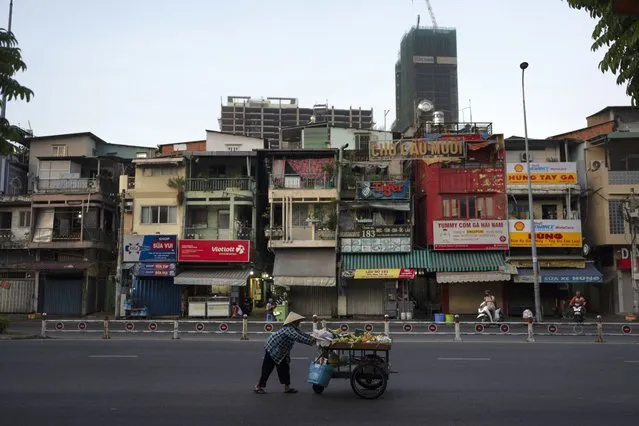 A fruit vendor pushes her cart along the street as buildings under construction are seen in the distance in Ho Chi Minh City, Vietnam, January 12, 2024. (Photo by Jae C. Hong/AP Photo)