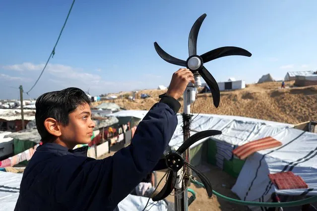 Displaced Palestinian teenager Hussam Al-Attar, nicknamed by people 'Newton', works on wind turbines, that he uses to light up his shelter during power cut, at a tent camp in Rafah, in the southern Gaza Strip, on February 6, 2024. (Photo by Ibraheem Abu Mustafa/Reuters)
