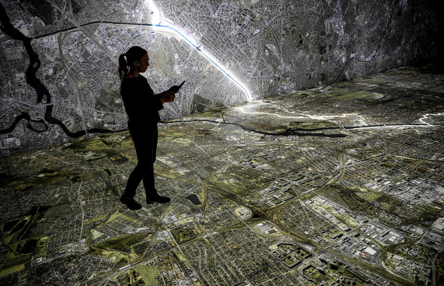 A young woman walks with a tablet over an illuminated aerial photograph of Berlin, marking the course of the Wall and places that had to do with the Stasi in Berlin, Germany on March 25, 2019. The show with the title “Stasi in Berlin – Surveillance and Repression in East and West” will show the hidden infrastructure of the Stasi and will be opened on 28 March 2019 in the Hohenschönhausen Memorial. (Photo by Britta Pedersen/dpa-Zentralbild for “New Exhibition: Hidden Stasi Meetings, Aerial Photo, Tablets”)