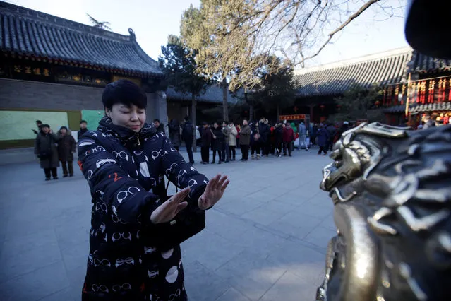 A woman closes her eyes and walks to touch a statue of a dragon for good fortune on the fifth day of the Chinese Lunar New Year at Baiyun Temple in Beijing, China, February 1, 2017. (Photo by Jason Lee/Reuters)