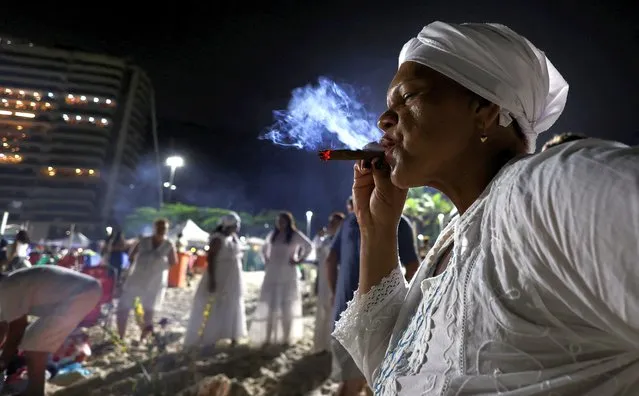 A woman smokes as people make offerings to the Afro-Brazilian goddess of the sea, Lemanja, at Copacabana beach during New Year celebrations, in Rio de Janeiro, Brazil on December 31, 2022. (Photo by Aline Massuca/Reuters)