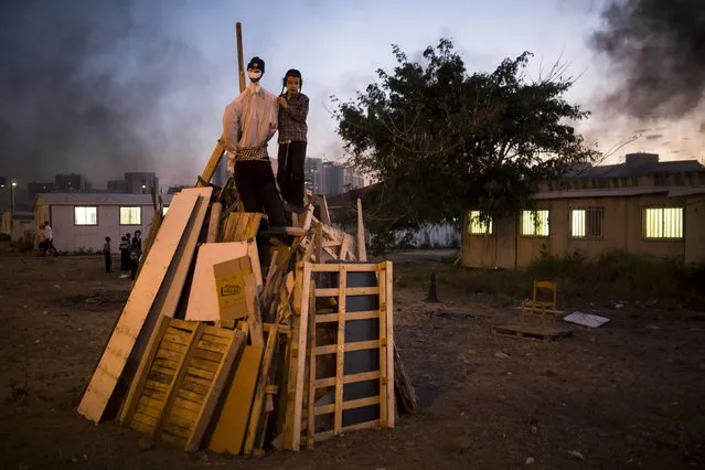 An ultra-Orthodox Jewish boy stands on a pile of wood to be burnt later as part of celebrations for the Jewish holiday of Lag Ba'Omer in Ashdod May 6, 2015. The holiday, which marks the end of a plague in the Middle Ages that killed thousands of disciples of a revered rabbi in the holy land, is celebrated by lighting bonfires across the country. (Photo by Amir Cohen/Reuters)