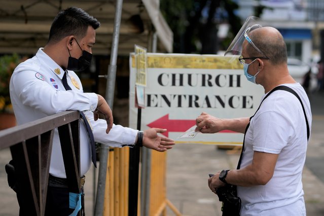A man shows his vaccine card to enter the Santo Domingo Church in Quezon city, Philippines as religious activities reopen with health restrictions on Thursday, September 16, 2021. The government starts the pilot run of granular or more localized lockdowns starting Thursday in the capital as they try to open up the economy while controlling the surge of COVID-19 infections. (Photo by Aaron Favila/AP Photo)