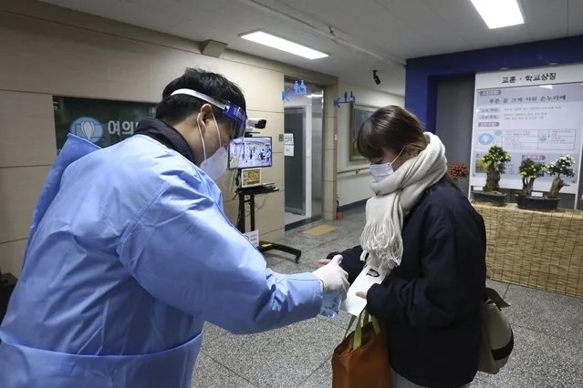 A teacher gives a hand sanitizer to a South Korean student before the College Scholastic Ability Test at a high school in Seoul Thursday, November 18, 2021. About 510,000 high school seniors and graduates across the country are expected to take the annual highly competitive university entrance exam. (Photo by Chung Sung-Jun/Pool Photo via AP Photo)
