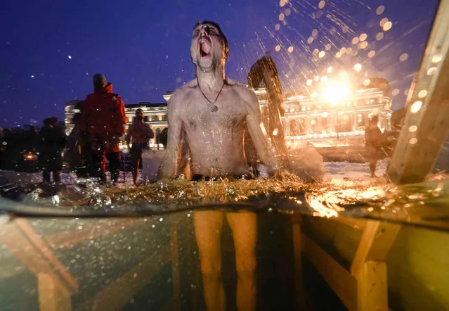 A Russian Orthodox believers dips in the icy water during a traditional Epiphany celebration in St. Petersburg, Russia, Wednesday, January 19, 2022. Thousands of Russian Orthodox Church followers plunged into icy rivers and ponds across the country to mark Epiphany, cleansing themselves with water deemed holy for the day. The temperature in St. Petersburg is –1C (30F). (Photo by Dmitri Lovetsky/AP Photo)