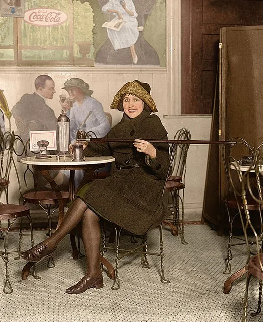 Woman seated at a soda fountain table pouring alcohol into a cup from a cane, with a large Coca-Cola advertisement on the wall, 13th February 1922. (Photo by Tom Marshall/Mediadrumworld)