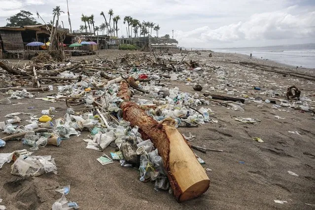 Plastic trashes and discarded wood that washed ashore are seen in Berawa Beach, Bali, Indonesia on December 12, 2021. Tons of marine pollutions washed ashore along the coastline during monsoon season making Bali's popular beach covered with plastic rubbish, woods and other discarded materials. (Photo by Johannes P. Christo/Anadolu Agency via Getty Images)