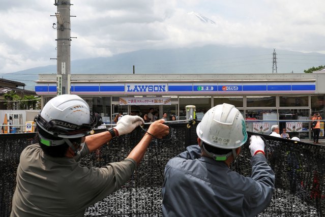 Workers erect a barrier to block the view of a popular Mount Fuji photo spot, near a convenience store in Fujikawaguchiko town, Yamanashi prefecture, Japan, on May 21, 2024. (Photo by Kim Kyung-Hoon/Reuters)