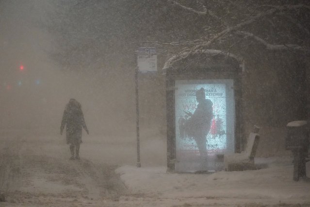A woman walks to a bus shelter on Dr. Martin Luther King Drive as a man waits in the shelter during the pre-dawn hours Wednesday, February 2, 2022, in Chicago. A major winter storm with millions of Americans in its path brought a mix of rain, freezing rain and snow to the middle section of the United States as airlines canceled hundreds of flights, governors urged residents to stay off roads and schools closed campuses. (Photo by Charles Rex Arbogast/AP Photo)