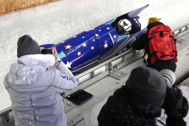 Coaches take photos as Elana Meyers Taylor of the United States speeds down the track during a 2-woman bobsled training at the 2022 Winter Olympics, Tuesday, February 15, 2022, in the Yanqing district of Beijing. (Photo by Mark Schiefelbein/AP Photo)