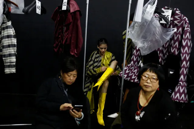 A model puts on her boots before the JD & Uyen fashion show by Han Dongyang at China Fashion Week in Beijing, China March 29, 2017. (Photo by Thomas Peter/Reuters)