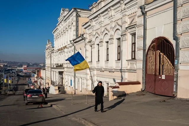 A man waves a Ukraine flag in downtown in Kharkiv, Ukraine, Thursday, February 24, 2022. (Photo by Salwan Georges/The Washington Post)