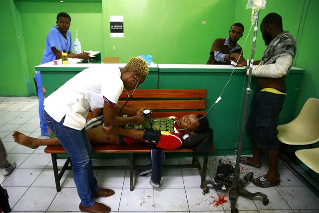 Jean Renel Joseph is tended too at the General Hospital emergency room after he was shot, in Port-au-Prince, Haiti, Thursday, April 25, 2019. Renel Joseph was shot last night while sitting with his friends near his home. Armed men open fire into the crowd and killed several people in the Carrefour-Feuille district of Port-au-Prince. (Photo by Dieu Nalio Chery/AP Photo)