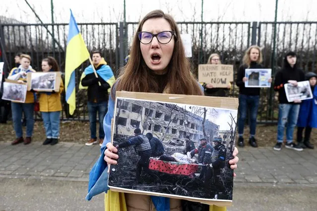 Anti-war protester holds a placard during a demonstration against Russia's invasion of Ukraine in front of the NATO headquarters in Brussels on March 16, 2022, as NATO Defence Ministers hold a meeting over the war in Ukraine. (Photo by Kenzo Tribouillard/AFP Photo)