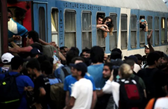 Tourists take pictures of migrants pushing to enter an international train from Thessaloniki to Budapest at Gevgelija train station in Macedonia, near the border with Greece,  July 19, 2015. (Photo by Ognen Teofilovski/Reuters)