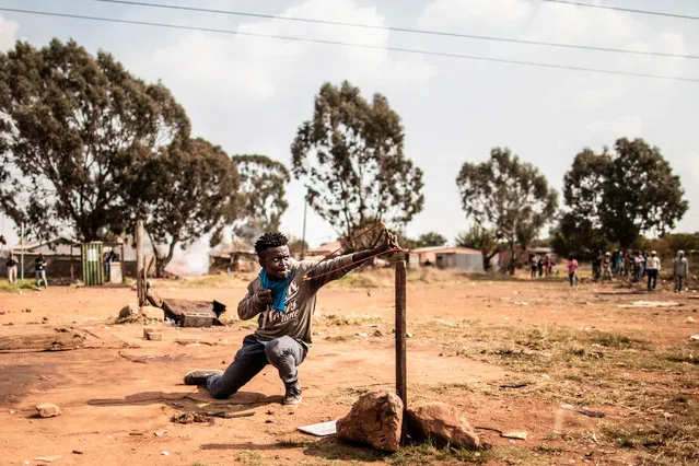 A protester uses a slingshot to hurl a stone at anti riot police during a demonstration on service delivery and housing in the community of Finetown in Ennerdale, on May 10, 2017. (Photo by Marco Longari/AFP Photo)