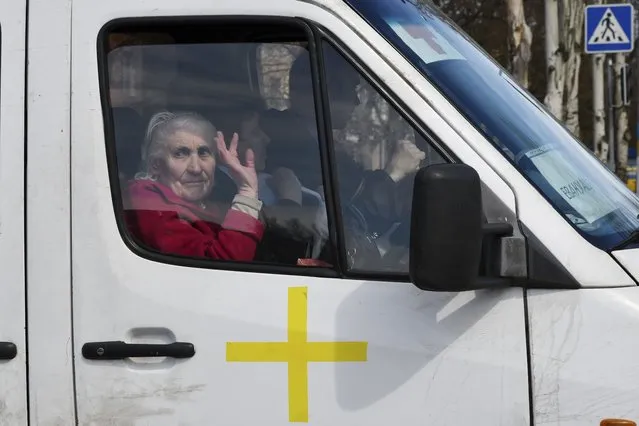 An elderly woman waves from a bus as civillians are evacuated, in Kramatorsk, Ukraine, Saturday, April 9, 2022. (Photo by Andriy Andriyenko/AP Photo)