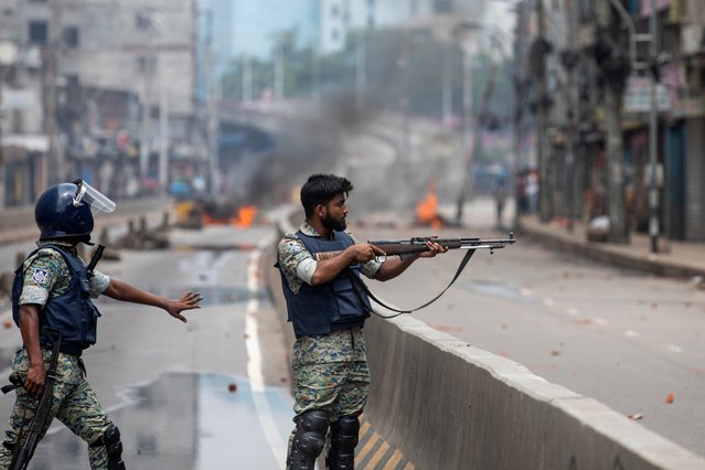 A policeman aims his weapon at protesters during a curfew imposed following violence during protests against Prime Minister Sheikh Hasina and her government, in Dhaka, Bangladesh, Monday, August 5, 2024. (Photo by Rajib Dhar/AP Photo)