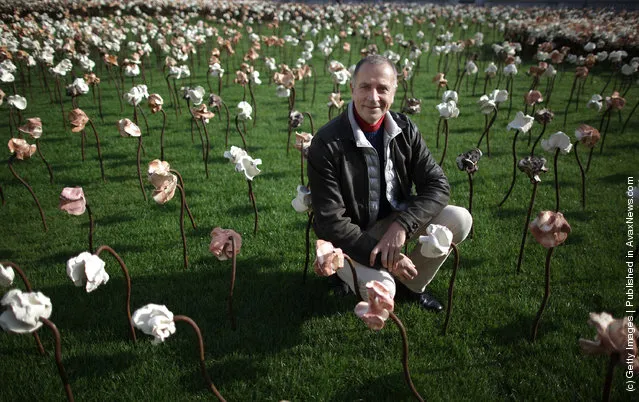 London based Chilean artist Fernando Casasempere poses with his 'Out of Sync' art installation on a grass meadow at Somerset Housein London