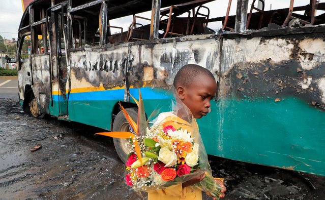 A boy carries a bouquet of flowers as he walks past a bus torched by unknown people ahead of protests by supporters of Kenya's opposition leader Raila Odinga of the Azimio La Umoja (Declaration of Unity) One Kenya Alliance, in a nationwide protest over cost of living and President William Ruto's government in Nairobi, Kenya on May 2, 2023. (Photo by Thomas Mukoya/Reuters)