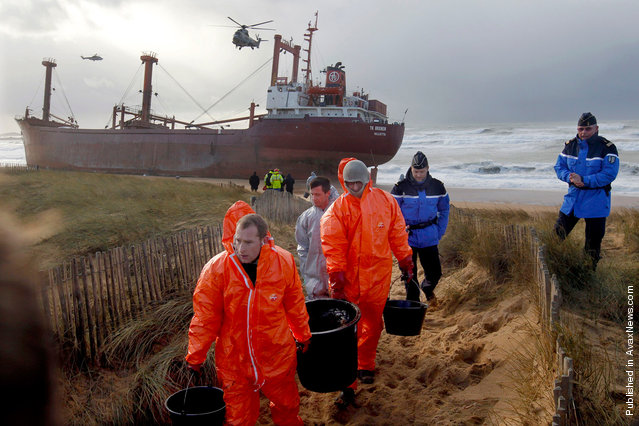 Workers clean the beach after the Maltese-registered TK Bremen ran aground on Kerminihy beach, on December 16, 2011