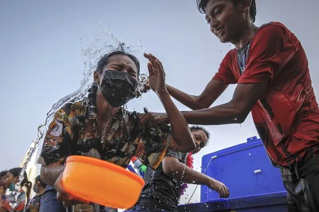 Anti government protesters splash water on each other as they celebrate the traditional Songkran new year festival during a protest in Bangkok, Thailand, 13 April 2022. Protesters held their own water splashing celebrations as the government imposed a ban on the traditional festivities of water splashing in public as a precaution against the ongoing rapid spread of the COVID-19 Omicron coronavirus variant. Songkran, Thai new year festival, also known as the water festival, falls annually on 13 April, and is traditionally celebrated with people splashing water and putting powder on each other's faces as a symbolic sign of cleansing and washing away the sins from the past year. (Photo by Diego Azubel/EPA/EFE)