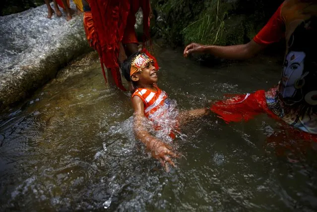 Hindu devotees help a boy take a holy dip on the Bagmati River during the “Bol Bom” pilgrimage in Kathmandu August 10, 2015. (Photo by Navesh Chitrakar/Reuters)