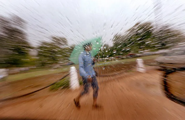 An Indian boy is seen through a window with raindrops as he rushes for shelter to protect him from a first monsoon shower in New Delhi, India, July 2, 2014. Indian meteorological department forecast that the monsoon is expected to reach the national capital in a day or two. (Photo by Harish Tyagi/EPA)