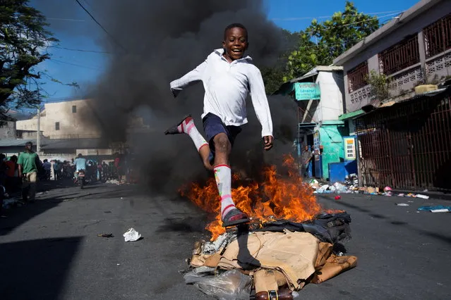 A boy jumps a barricade in flames near the Petionville market, during a protest day in Port-au-Prince, Haiti, 17 October 2019. Port-au-Prince woke up with numerous barricades, roadblocks and intentional fires at the start of a new mobilization day called by opposition groups against President Jovenel Moise. The mobilization day has been raised by the opposition as a day of “general uprising” of the popular and peasant classes against the head of state. (Photo by Orlando Barria/EPA/EFE)