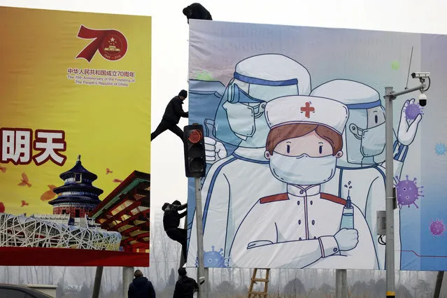 Workers put up government propaganda to fight against the viral outbreak in Beijing, China on Thursday, February 20, 2020. A viral outbreak that began in China has infected more than 75,000 people globally. The World Health Organization has named the illness COVID-19, referring to its origin late last year and the coronavirus that causes it. (Photo by Ng Han Guan/AP Photo)
