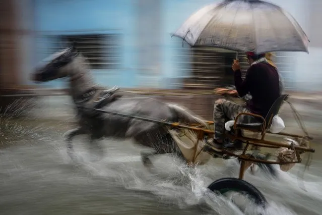 A horse pulls a buggy with passengers through a street flooded by heavy rains, in Havana, Cuba, Friday, June 3, 2022. Tropical storm Alex has drenched Cuba with almost non-stop rain for the last 24 hours as it moves across the southeastern Gulf of Mexico toward Florida. (Photo by Ramon Espinosa/AP Photo)