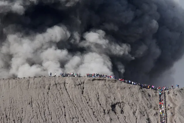 People standing on the edge of the crater while watching the eruption of Mount Bromo in Probolinggo, Indonesia, July 12, 2016. (Photo by Ari Bowo Sucipto/Reuters/Antara Foto)