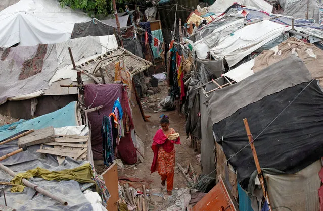 A girl carries flat bread for lunch as she walks past makeshift tents in a slum in Karachi, Pakistan July 12, 2016. (Photo by Akhtar Soomro/Reuters)