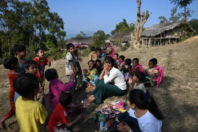 This photo taken on February 4, 2020 shows children playing as they surround their teacher in front of their school in Toe Lawt in Lahe township in Myanmar's Sagaing region. (Photo by Ye Aung Thu/AFP Photo)
