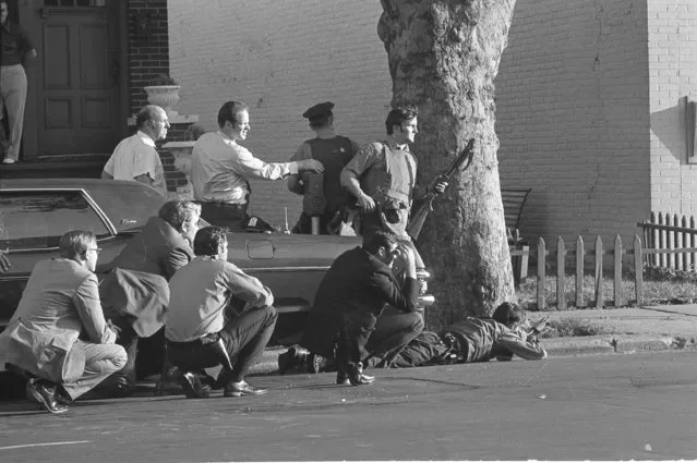 New York City police surround a small Brooklyn branch bank, August 22, 1972, ready with arms behind a tree as two gunmen who described themselves as homosexuals, hold eight hostages inside the bank. The incident which began as a bank robbery was quickly cut off as some 200 policemen swarmed the scene. (Photo by Dave Pickoff/AP Photo)