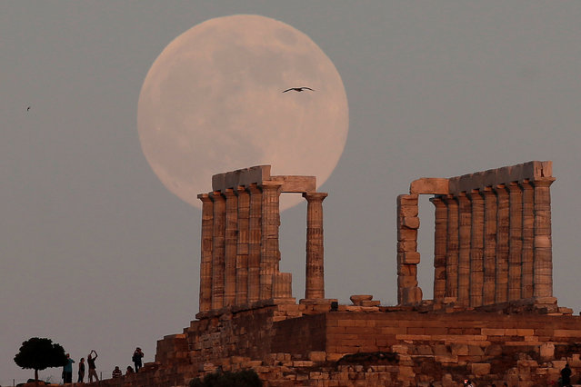 A nearly full moon rises over the Temple of Poseidon, the ancient Greek god of the seas, in Cape Sounion, east of Athens, Greece, July 8, 2017. (Photo by Costas Baltas/Reuters)