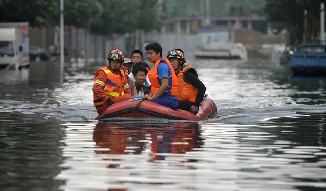 In this Thursday, July 21, 2016, photo, rescuers use a raft to transport people along a flooded street in Shenyang in northeastern China's Liaoning Province. Dozens of people have been killed and dozens more are missing across China after a round of torrential rains swept through the country earlier this week, flooding streams, triggering landslides and destroying houses. (Photo by Chinatopix via AP Photo)