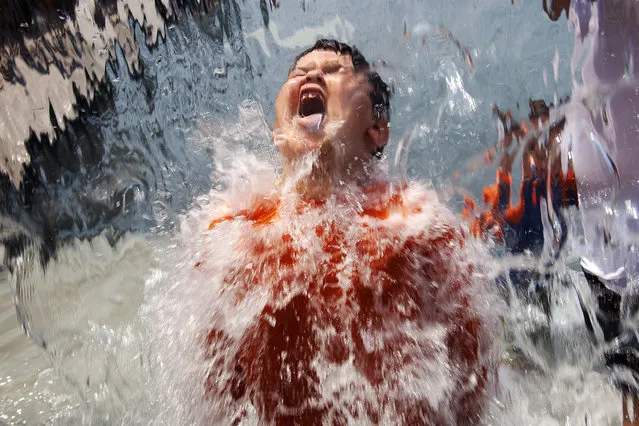 Lucas Olivo, 6, of Cheverly, Md., opens his mouth wide while running through a wall of water at Yards Park in Washington, on Thursday, June 21, 2012. (Photo by Jacquelyn Martin/AP Photo)