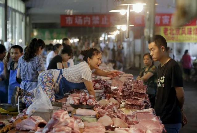 A vendor tries to get a piece of pork for a customer at a market in Beijing, China, August 12, 2015. China's consumer inflation in August edged up more than expected from a year earlier, but producer prices fell for the 42nd straight month in the latest sign that deflation remains a significant risk for the world's second-largest economy. (Photo by Jason Lee/Reuters)