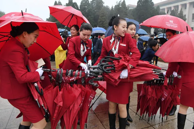 Attendants collect umbrellas after accompanying delegates to the Great Hall of the People for the opening ceremony of the 19 th Communist Party Congress in Beijing on October 18, 2017. President Xi Jinping declared China is entering a “new era” of challenges and opportunities on October 18 as he opened a Communist Party congress expected to enhance his already formidable power. (Photo by Greg Baker/AFP Photo)
