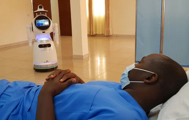 A high-tech robot developed by Zora Bots, a Belgium-based company, and donated by the United Nations Development Program (UNDP) prepares to check the temperature of a health worker during a demonstration at the Kanyinya treatment centre that treats coronavirus disease (COVID-19) patients, in Kigali, Rwanda on May 29, 2020. (Photo by Clement Uwiringiyimana/Reuters)