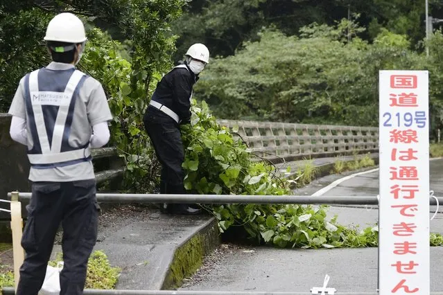 Workers clear debris broken by strong winds as a powerful typhoon hits the area in Kumamoto, southwestern Japan, Monday September 19, 2022. (Photo by Kyodo News via AP Photo)
