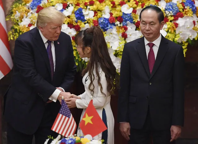 U.S. President Donald Trump, left, shakes hands with Nguyen Thi Phuong Thao, center, chairwoman of Vietnam's private airliner VietJetAir as Vietnamese President Tran Dai Quang looks on during a signing ceremony in Hanoi, Vietnam Sunday, November 12, 2017. (Photo by Hoang Dinh Nam/Pool Photo via AP Photo)