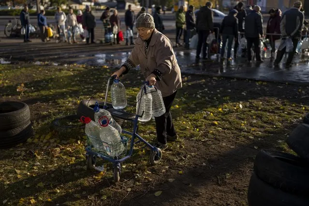 Catherine, 75, pushes her walker loaded with plastic bottles after refilling them in a tank, in the center of Mykolaiv, Monday, October 24, 2022. (Photo by Emilio Morenatti/AP Photo)