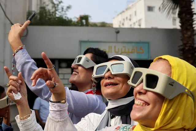 People use special protective glasses to observe and watch a partial solar eclipse by  in Cairo, Egypt on October 25, 2022. (Photo by Mohamed Abd El Ghany/Reuters)