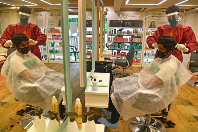 Staff at Shiva's Signature hair salon wearing Personal Protective Equipment (PPE) suit and face shield attends a customer after personal grooming services were allowed to resume following relaxation of lockdown norms amidst Covid-19 coronavirus pandemic, in Mumbai on June 28, 2020. India now has more than 500,000 confirmed coronavirus cases, according to government figures released on June 27 that showed a record daily leap of 18,500 new infections. (Photo by Indranil Mukherjee/AFP Photo)