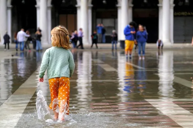 A little girl walks a through water in a flooded St. Mark's Square during seasonal high water in Venice, Italy on October 25, 2022. (Photo by Manuel Silvestri/Reuters)
