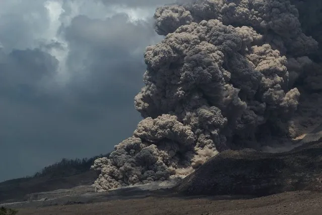 Super heated giant ash cloud spew from the crater of Mount Sinabung volcano threatening villages during an eruption on October 17, 2014 as seen from Simpang Empat district on Sumatra island. In February, Sinabung's eruption killed about 17 people and forced more than 33,000 others to flee their homes. (Photo by Sutanta Aditya/AFP Photo)